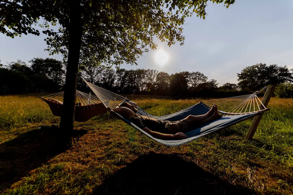 A person resting in a hammock under a tree at sunset in the retreat meadow